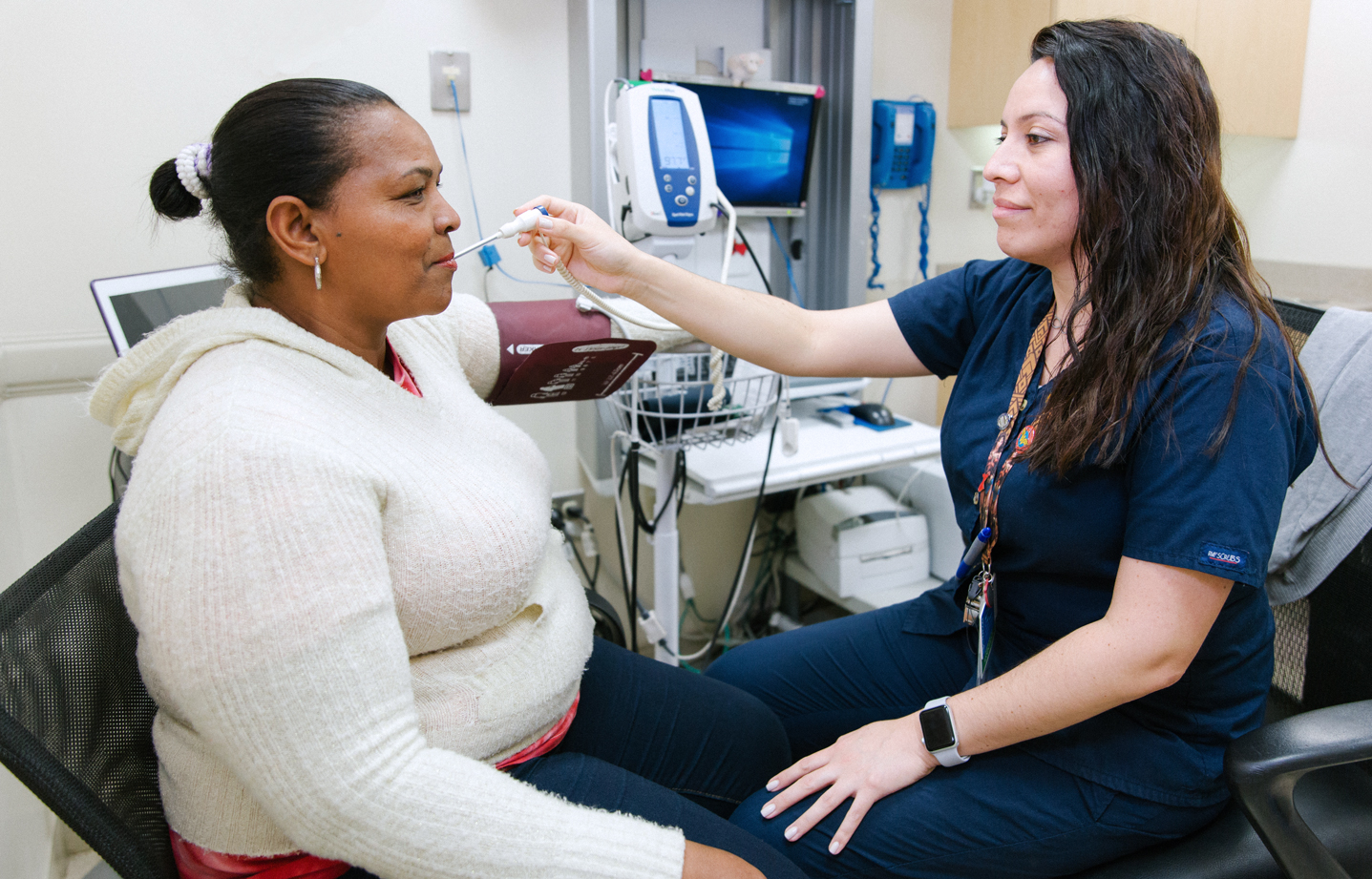 Grace Pelaez, Medical Assistant, BronxCare Dr. Martin Luther King, Jr. Health Center, taking temperature of patient.